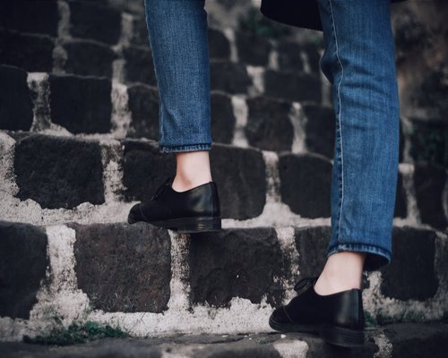 Person wearing comfortable shoes walking up stone stairs in an urban park